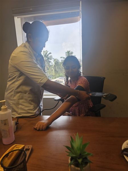 A nurse checking an employee's blood pressure at a vaccination camp